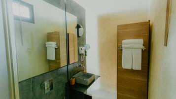 A modern bathroom with a large mirror, a wooden door, a sink, and a towel rack.