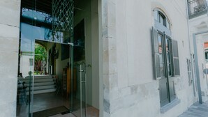 A building entrance with a glass door, a metal gate, and a small step leading up to the door. - Casa Mespilea Guest House (Paphos)