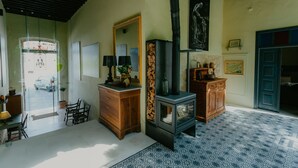 A room with a wooden dresser, a mirror, a fireplace, and a door with a blue frame. - Casa Mespilea Guest House (Paphos)