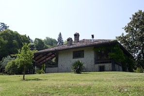 Ein Steinhaus mit Ziegeldach, einer Holzpergola und einem Rasen.
