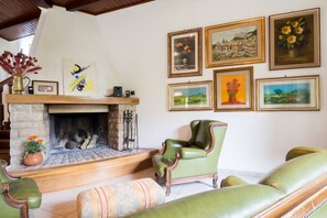 A cozy living room with a fireplace, green leather armchairs, and framed artwork on the wall. - Opulent Villa Private Heated Pool and Park, Volley Ball, Table Tennis, Whirlpool (Terni)