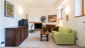 Een woonkamer met een groene bank, een houten kast en een open haard.