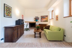 Ein Wohnzimmer mit einem grünen Sofa, einem Holzschrank und einem Kamin.