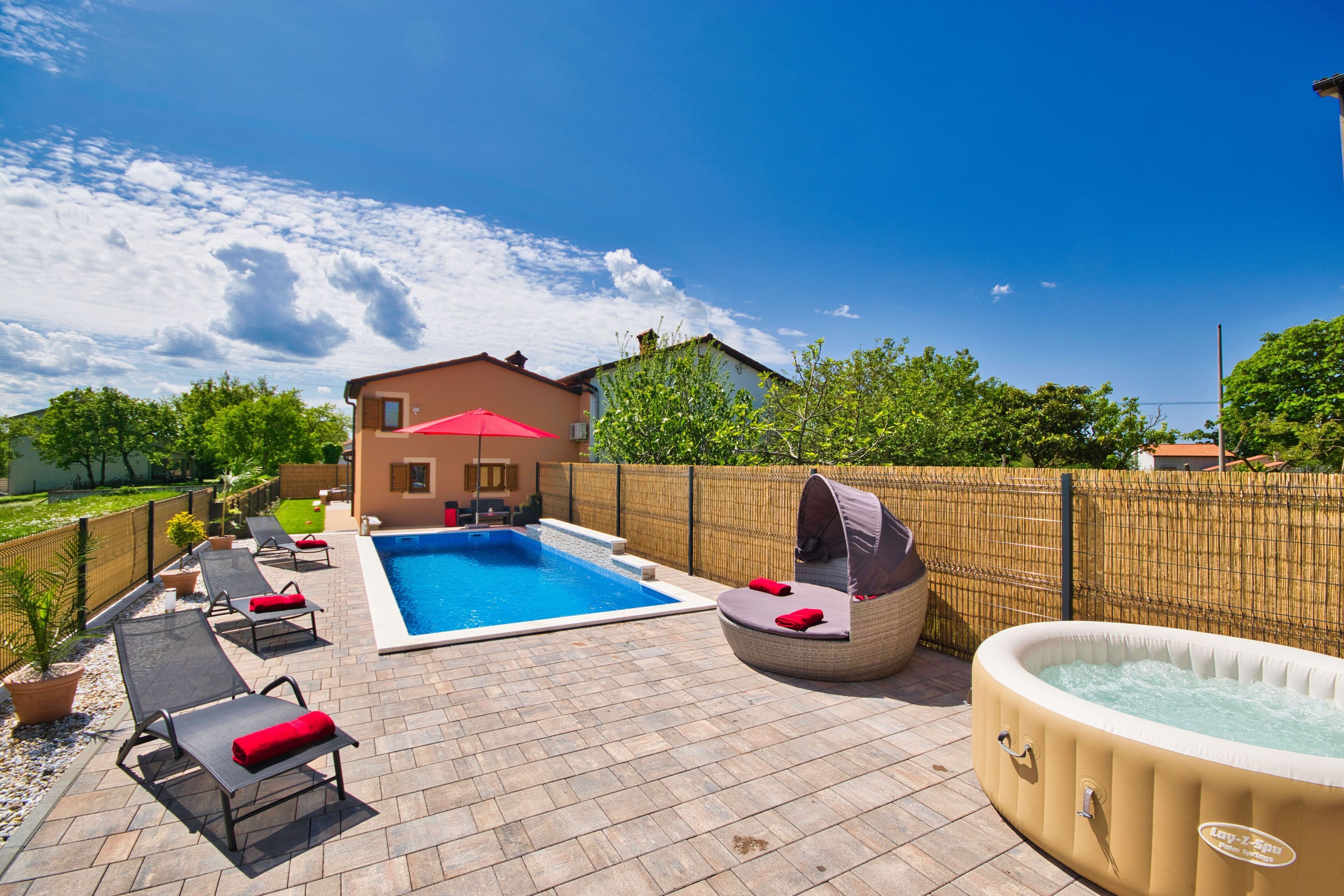 Ein Garten mit Swimmingpool, Liegestühlen, Whirlpool und einem Haus.