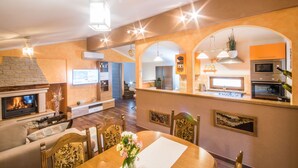 A spacious living room with a fireplace, dining area, kitchen, and a staircase leading to an upper floor. - Cozy family-friendly fenced villa, pool and outdoor jacuzzi (Karojba)