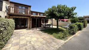 A two-story building with a patio area featuring outdoor seating and a tree. - corner house for 7 persons, 4 bedrooms, in TAMARIS, WIFI, 500m from the sea in Portiragnes plage (PORTIRAGNES)