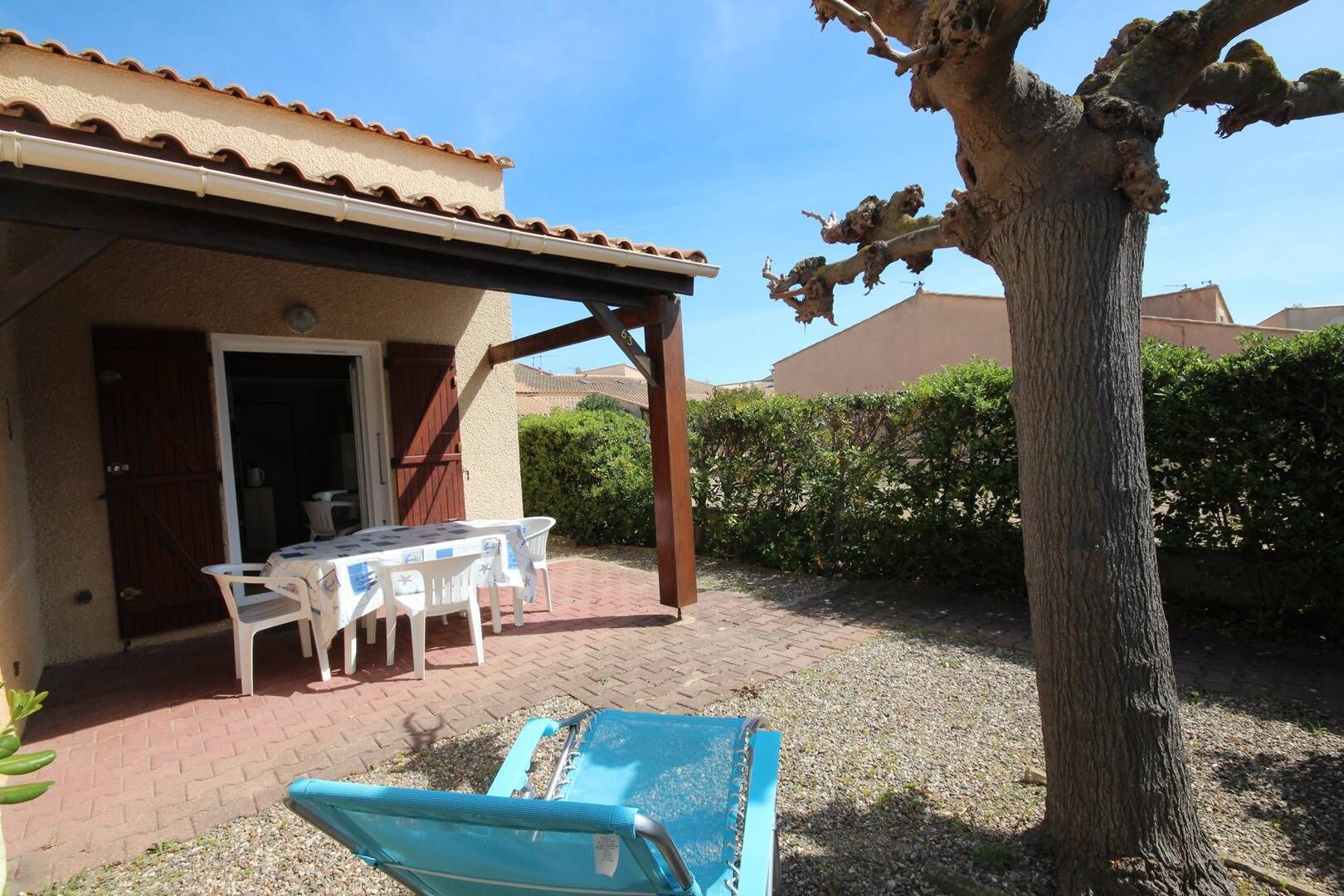 A patio with a table and chairs, a covered area, and a tree.