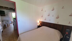 Une chambre à coucher avec un lit, une table de chevet avec une lampe et un mur décoré d’autocollants représentant des voiliers.