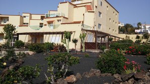 Un bâtiment doté de nombreux balcons, d’un espace extérieur couvert et d’un jardin agrémenté de cactus et de plantes à fleurs.