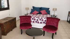 A bedroom with a bed, two bedside tables with lamps, a wooden chest, two armchairs, and a small round table. - Independent studio in villa overlooking Monaco + parking in Monaco (beausoleil)