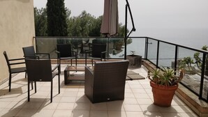 A balcony with wicker furniture, a potted plant, and a view of the sea. - Independent studio in villa overlooking Monaco + parking in Monaco (beausoleil)