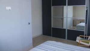 Une chambre à coucher avec un lit, une chaise, une armoire et un miroir.