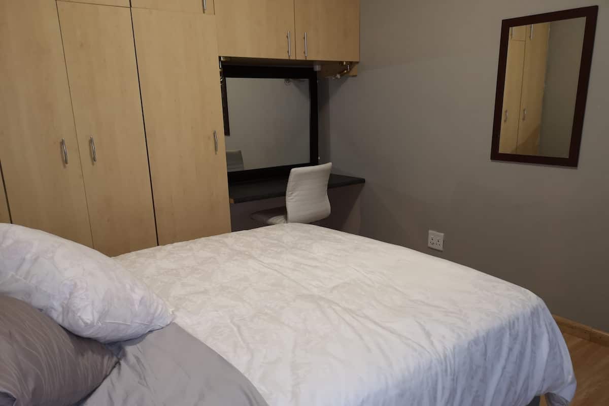 A bedroom with a bed, a desk, and a wardrobe.