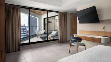 Een moderne hotelkamer met een groot raam, een flatscreen televisie, een bureau met een stoel en een bed.
