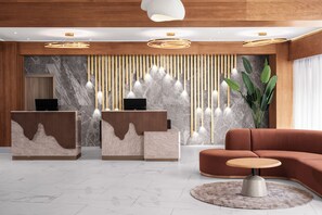 A modern reception area with two reception desks, a sofa, and a round table.