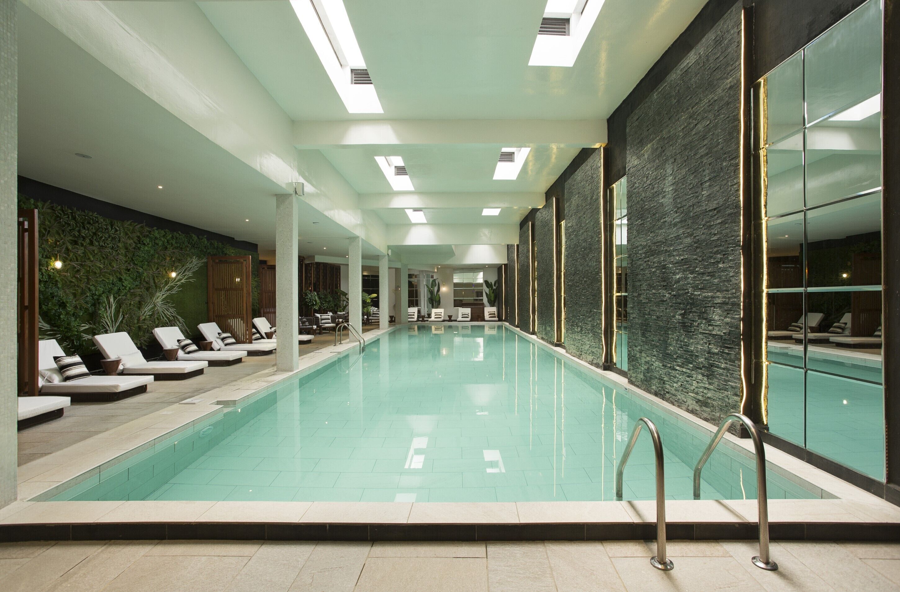 A swimming pool with lounge chairs and a stone wall.