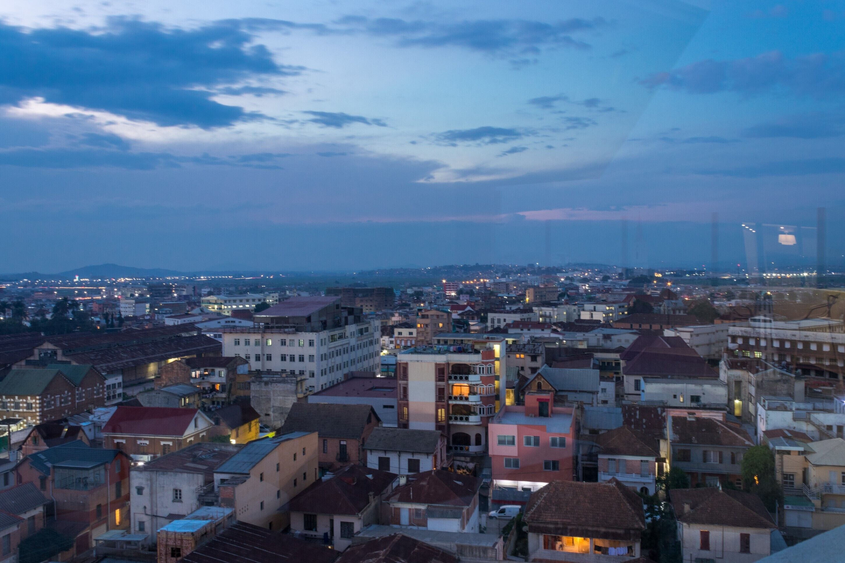 A cityscape at dusk with buildings and a bridge in the background.