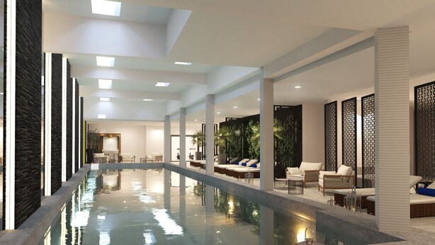 Uma área interna de piscina moderna com piscina central, assentos de descanso e teto alto com claraboias.