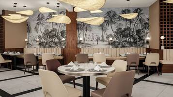 A restaurant with round tables, chairs, and hanging pendant lights.