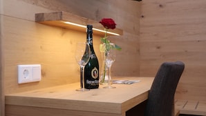 A wooden table with a bottle of champagne, a glass, and a vase with a red rose. - Gasthof-Pension Kerber (Fürstenstein)
