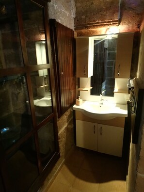 A bathroom with a wooden door, a sink, a mirror, and a towel rack. - Osmanoglu Hotel (Guzelyurt)