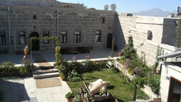 Un patio con edificios de piedra, una fuente y plantas en macetas.