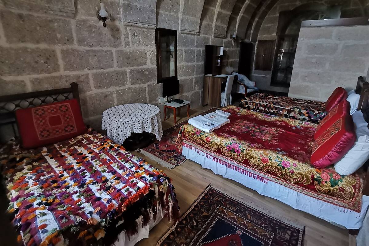 Una habitación con una cama grande, una cama más pequeña, una mesa redonda y una silla.