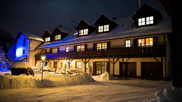 A snow-covered building with multiple windows and a covered walkway. - Pension Aufeld (Landsberg am Lech)