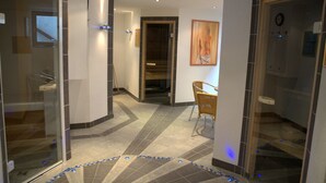 A hotel hallway with a glass door, a wooden chair, and a tiled floor. - Pension Aufeld (Landsberg am Lech)