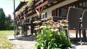 A patio area with outdoor seating and a garden with flowers. - Pension Aufeld (Landsberg am Lech)