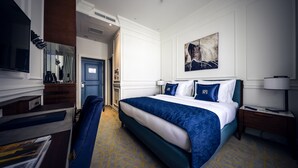 Habitación de hotel con una cama grande, un escritorio con silla, un televisor y un cuadro en la pared.