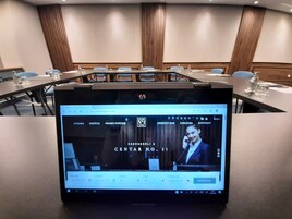 Un salón de conferencias de hotel con una pantalla grande mostrando la página web del hotel.