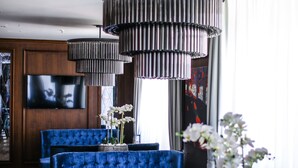 Una sala de estar moderna con sofás tapizados en azul, piso de madera, un televisor grande y un aplique de techo.