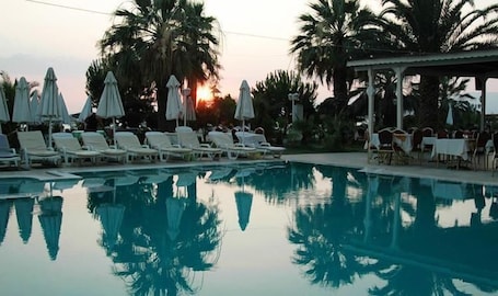 Una piscina techada, una piscina al aire libre, sombrillas
