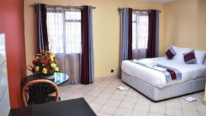 Ein Hotelzimmer mit einem Bett, einem kleinen Tisch mit Stuhl und einer Blumenvase.