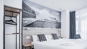 A modern hotel room with a large bed, a wardrobe, a small table, and a wall-mounted shelf. - Mirotza Rooms (Orio)