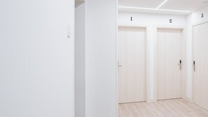 A hallway with three numbered doors, white walls, and a wooden floor. - Mirotza Rooms (Orio)