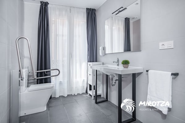 Un baño moderno con inodoro, bidé, lavabo y espejo.