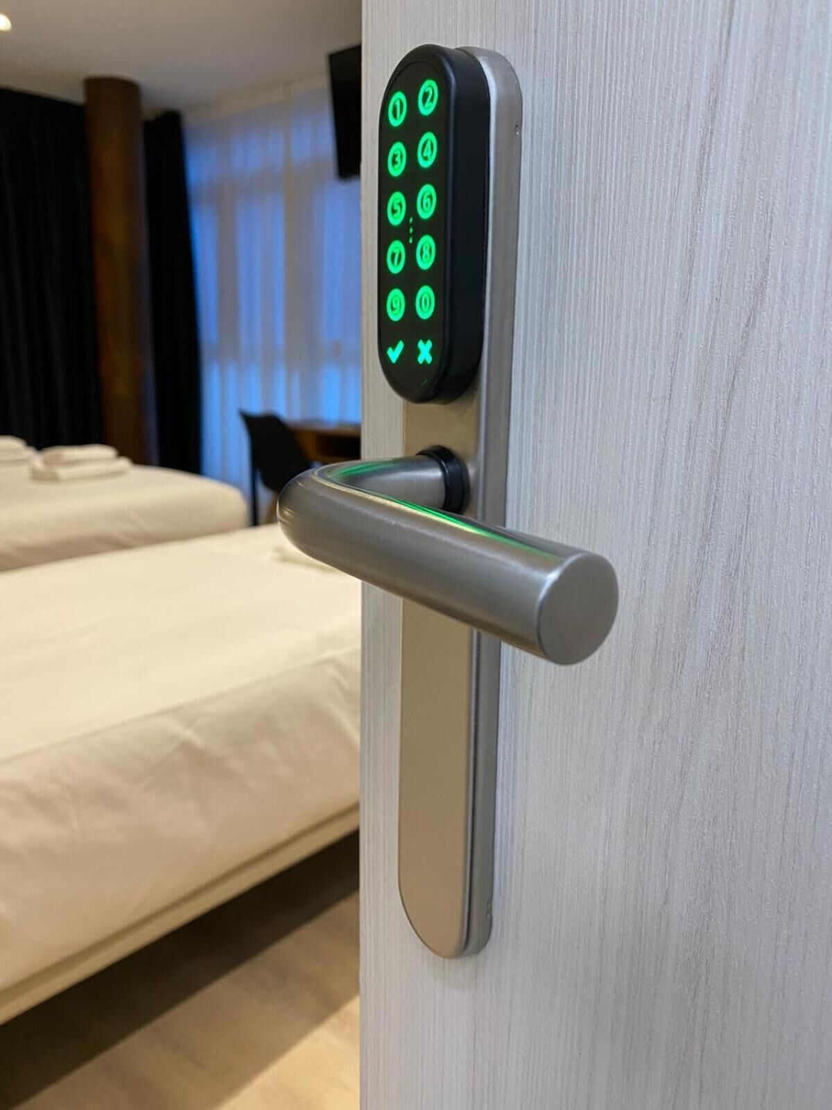 A modern hotel room with a digital keypad lock on the door.