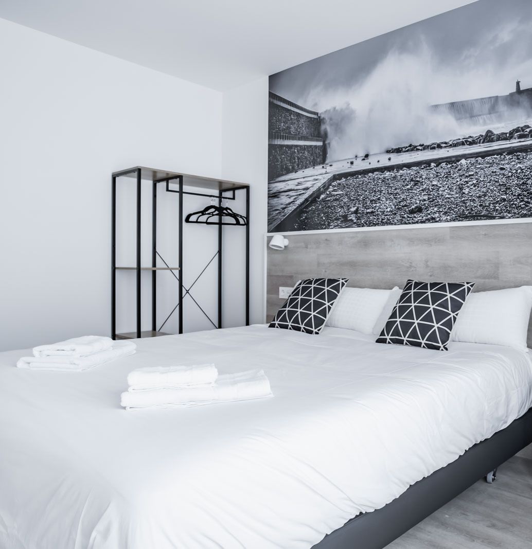 Um quarto moderno com uma cama grande, cabeceira e um guarda-roupa fixado na parede.