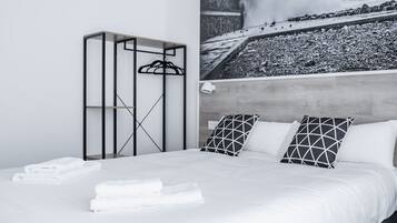 Um quarto moderno com uma cama grande, cabeceira e um guarda-roupa fixado na parede.