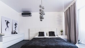 Un dormitorio moderno con una cama grande, cabecera blanca y una lámpara esférica colgante.