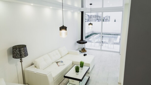 Una sala de estar moderna con un sofá blanco, una mesa de centro de vidrio y lámparas colgantes.