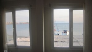 Habitación de hotel con dos camas, vista al mar y una playa visible a través de las ventanas.