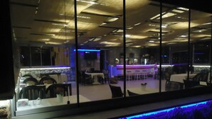 Un interior moderno con una zona de bar, asientos y vistas amplias a través de grandes ventanales.