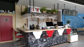 A bar area with a counter, bar stools, a computer, and a menu board.