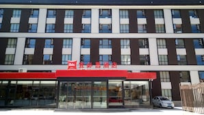 A hotel with a modern facade, featuring a prominent red and white sign with Chinese characters.