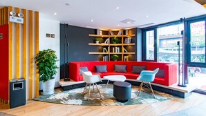 A modern lobby with a red sofa, a white table, and a bookshelf. - Ibis Wuxi Taihu Square Hotel (Wuxi)