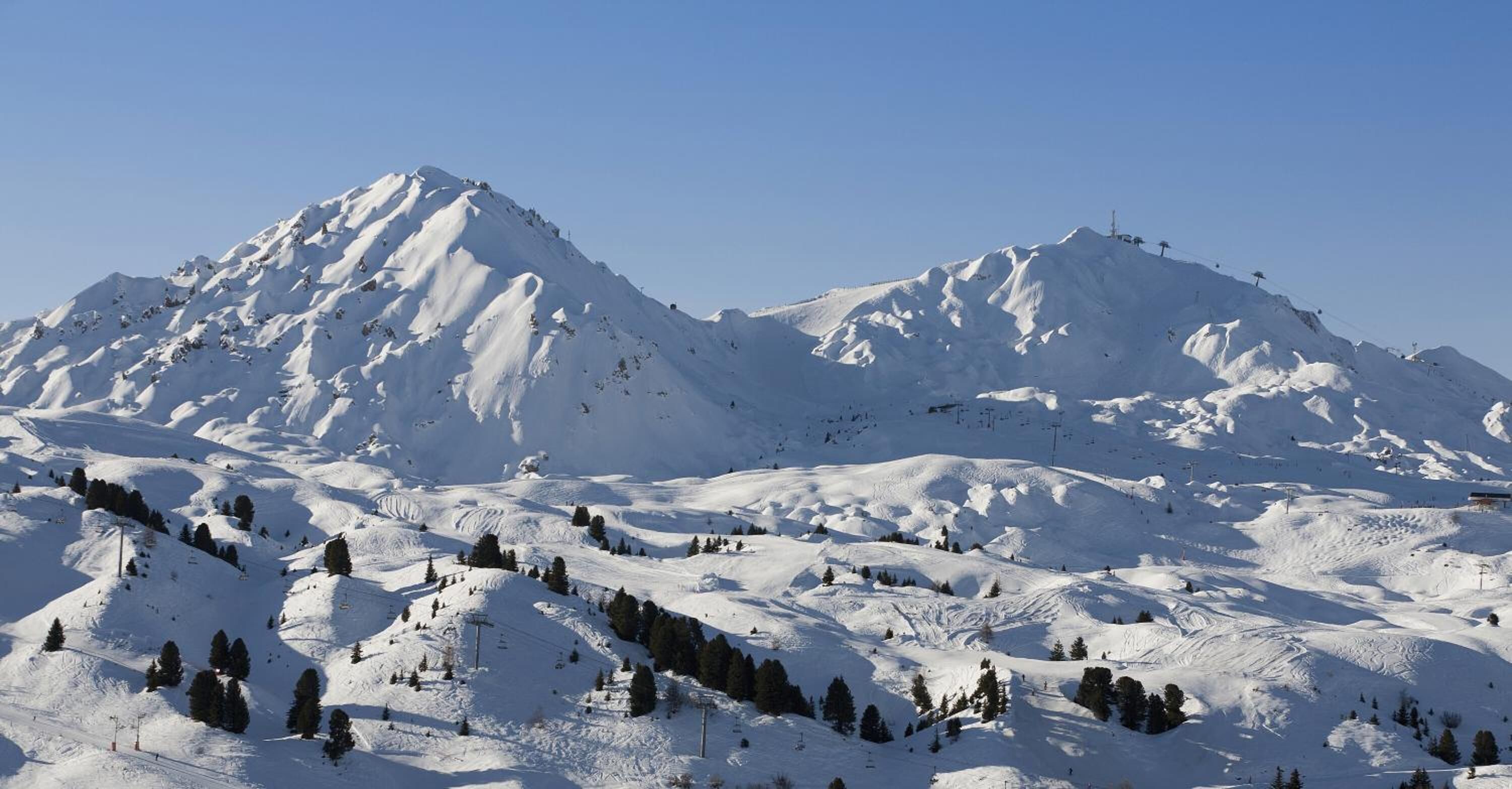 Une montagne enneigée, avec des pistes de ski et un télésiège.