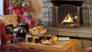 A cozy living room with a fireplace, a coffee table with breakfast items, and a helmet on the couch.